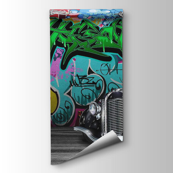 Black car with wheels in front of a colorful wall